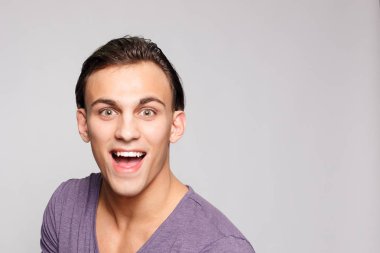 duygu, reklam ve insanlar kavramı - yakışıklı genç adam kameraya bakarak gri arka plan üzerinde. Seksi bir adam portresi. Mutlu erkek gülümseyen.