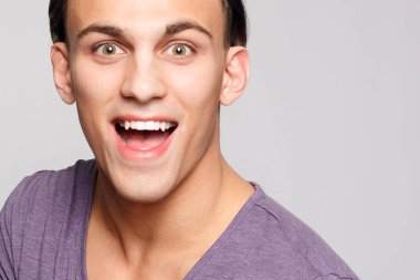 duygu, reklam ve insanlar kavramı - yakışıklı genç adam kameraya bakarak gri arka plan üzerinde. Seksi bir adam portresi. Mutlu erkek gülümseyen.