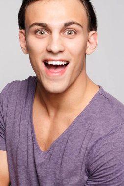 duygu, reklam ve insanlar kavramı - yakışıklı genç adam kameraya bakarak gri arka plan üzerinde. Seksi bir adam portresi. Mutlu erkek gülümseyen.