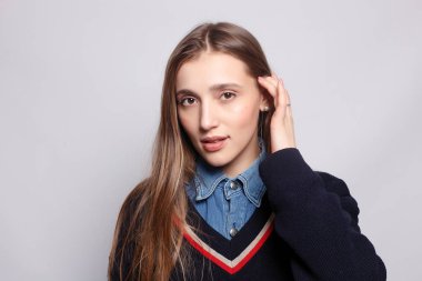 Güzel, neşeli bir kadın, sarışın, sıradan giyinmiş, kameraya tatmin edici bir şekilde bakıyor, mutlu. Güzel bir kadının stüdyo resmi. Boş bir stüdyo duvarında izole edilmiş..