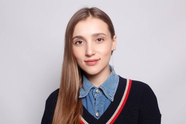 Güzel, neşeli bir kadın, sarışın, sıradan giyinmiş, kameraya tatmin edici bir şekilde bakıyor, mutlu. Güzel bir kadının stüdyo resmi. Boş bir stüdyo duvarında izole edilmiş..