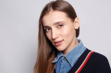 Güzel, neşeli bir kadın, sarışın, sıradan giyinmiş, kameraya tatmin edici bir şekilde bakıyor, mutlu. Güzel bir kadının stüdyo resmi. Boş bir stüdyo duvarında izole edilmiş..