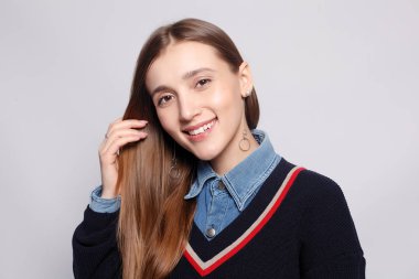 Güzel, neşeli bir kadın, sarışın, sıradan giyinmiş, kameraya tatmin edici bir şekilde bakıyor, mutlu. Güzel bir kadının stüdyo resmi. Boş bir stüdyo duvarında izole edilmiş..