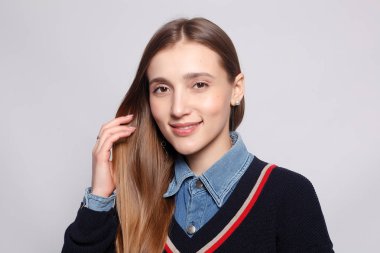 Güzel, neşeli bir kadın, sarışın, sıradan giyinmiş, kameraya tatmin edici bir şekilde bakıyor, mutlu. Güzel bir kadının stüdyo resmi. Boş bir stüdyo duvarında izole edilmiş..