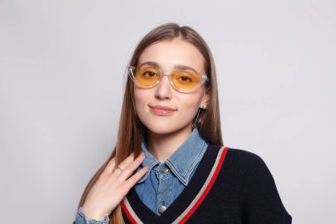 Güzel, neşeli bir kadın, sarışın, sıradan giyinmiş, kameraya tatmin edici bir şekilde bakıyor, mutlu. Güzel bir kadının stüdyo resmi. Boş bir stüdyo duvarında izole edilmiş..