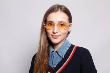 Güzel, neşeli bir kadın, sarışın, sıradan giyinmiş, kameraya tatmin edici bir şekilde bakıyor, mutlu. Güzel bir kadının stüdyo resmi. Boş bir stüdyo duvarında izole edilmiş..