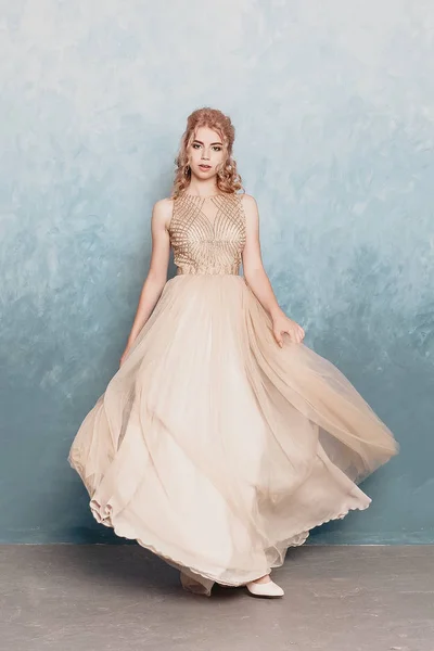 Fashion model in beautiful luxury beige flowing chiffon dress, Woman in long flying evening dress with a gown, Stunning fantasy model. Silk fabric waving on wind. Satin Cloth Flowing, Waves of a dress