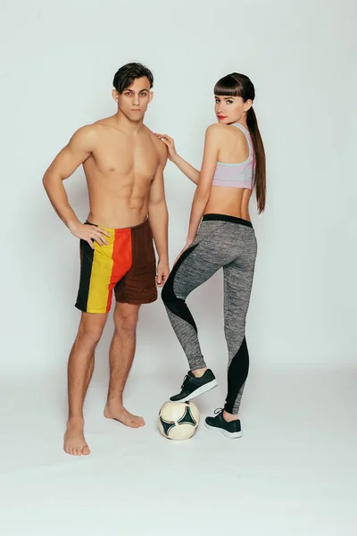 health, people, Sport and lifestyle concept - Young sportsmen couple woman and man in studio. Young and beautiful athletic woman and man on gray background