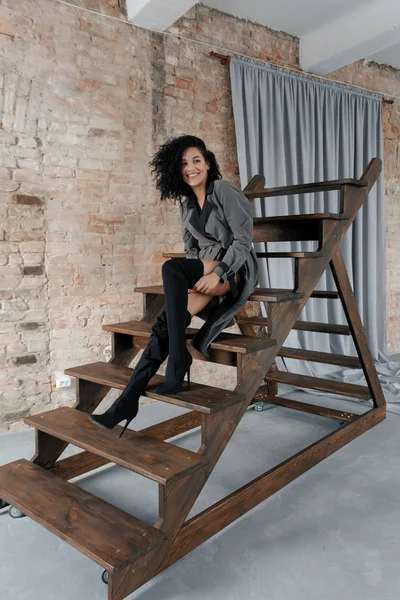 people, race, ethnicity and fashion concept - beauty black model posing in high boots. woman in gray raincoat and afro hairstyle