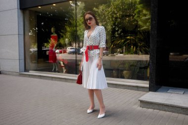 siyah lekeli beyaz elbise giyen güzel model bak esmer bir şehir sokak arka planda şık çanta el ile uyanma sırasında kadındır.