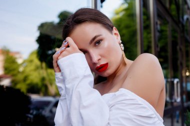 Esmer beyaz gömlek ve mavi pantolon giyiyor. İş kıyafeti. Casual bak. Vitrin yanında duruyor. Tüm vücut bak.