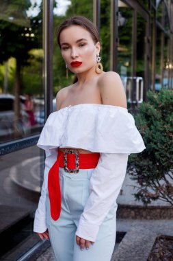 Esmer beyaz gömlek ve mavi pantolon giyiyor. İş kıyafeti. Casual bak. Vitrin yanında duruyor. Tüm vücut bak.