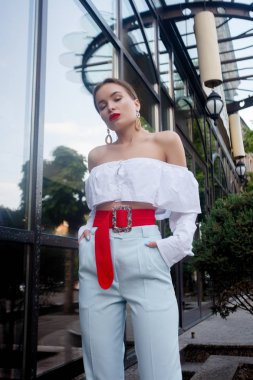 Esmer beyaz gömlek ve mavi pantolon giyiyor. İş kıyafeti. Casual bak. Vitrin yanında duruyor. Tüm vücut bak.