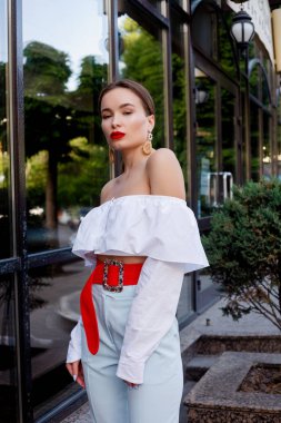 Esmer beyaz gömlek ve mavi pantolon giyiyor. İş kıyafeti. Casual bak. Vitrin yanında duruyor. Tüm vücut bak.