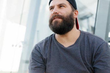 Closeup of smiling young man looking at camera. Portrait of a guy with beard who changes facial expressions. Proud and satisfied man with t-shirt looking at camera. clipart