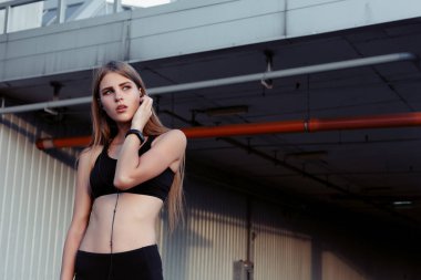 Kadın atlet dinlenme çalışmadan sonra şehirde alarak. Müzik ve gülerek seyir kulaklıklar ile spor Fitness kadında.