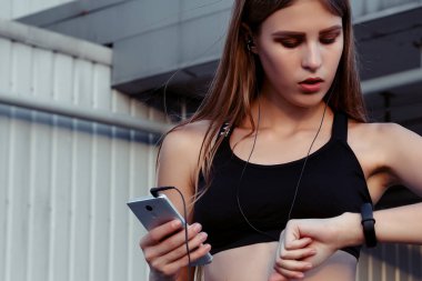 Kadın atlet dinlenme çalışmadan sonra şehirde alarak. Müzik ve gülerek seyir kulaklıklar ile spor Fitness kadında.