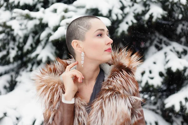 短い髪 美容スタイルの肖像画のエキゾチックな女性 冬の雪と雪に覆われた長いモミの木を背景に かわいい笑顔 物思いにふけるハゲ女 イブニング ドレスでポーズをとる女性 — ストック写真