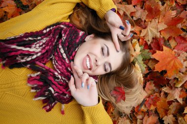Güzellik, insanlar, sezon ve sağlık kavramı - kırmızı sonbahar yaprakları sarı renk ile güzel kız yalan söylüyor