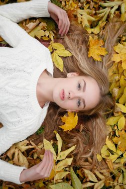 Güzellik, insanlar, sezon ve sağlık kavramı - güzel kız sarı sonbahar yaprak yalan söylüyor