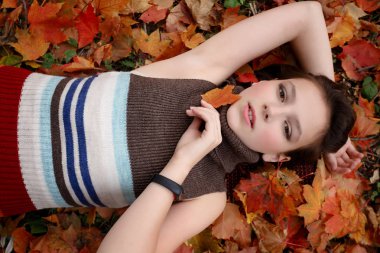 Güzellik, insanlar, sezon ve sağlık kavramı - sevimli küçük kız sarı sonbahar yaprak yalan söylüyor