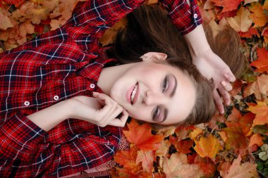 Güzellik, insanlar, sezon ve sağlık kavramı - kırmızı sonbahar yaprakları sarı renk ile güzel kız yalan söylüyor