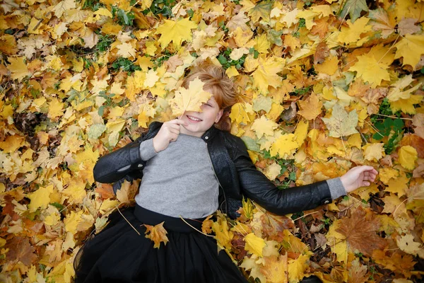 Güzellik, insanlar, sezon ve sağlık kavramı - sevimli küçük kız sarı sonbahar yaprak yalan söylüyor