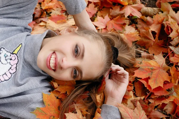 美しさ 健康の概念 かわいい女の子 黄色の秋葉に横たわっています — ストック写真