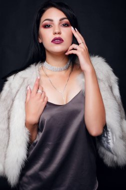 Kürk lüks aksesuarları ile bir güzel esmer kız moda portre. Güzellik modeli takı siyah arka plan ile. Kız beyaz vizon kürk manto. Güzel lüks kış kadın.