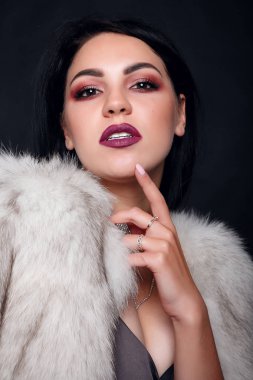 Kürk lüks aksesuarları ile bir güzel esmer kız moda portre. Güzellik modeli takı siyah arka plan ile. Kız beyaz vizon kürk manto. Güzel lüks kış kadın.