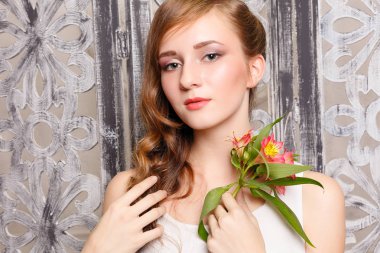 Gri arka plan üzerinde çiçekler ile genç güzel bayan. Cilt bakım kavramı. Studio bir yeşil gri bir arka plan üzerinde tatlı bir genç kız portresi çiçek el