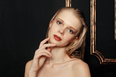 Güzellik moda modeli kız doğal makyaj ıslak saç siyah altın arka planda sıcak tonları. Moda makyaj ile genç kadın portresi