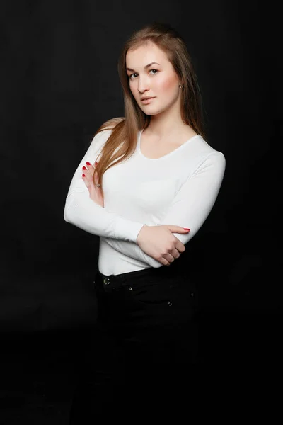 Youth, lifestyle and education concept. image of young hipster girl wearing blank white t-shirt and black jeans, black background.