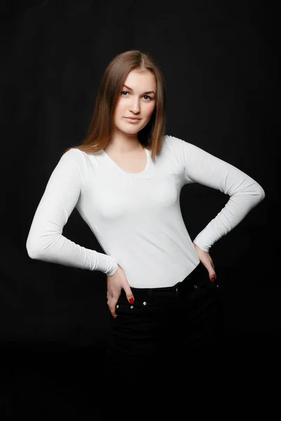 Youth, lifestyle and education concept. image of young hipster girl wearing blank white t-shirt and black jeans, black background.