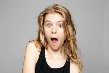 Çekici genç kız yüzünü dokunaklı. Fotoğraf gri arka plan üzerinde mükemmel cilt ile sarışın kız. Güzellik ve cilt bakım kavramı. Doğal makyaj ve temiz cilt olan güzel kadın