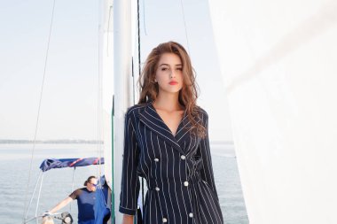 Çekici kız yaz gününde bir yatta. Yat poz çarpıcı romantik kadın moda portresi kapatın. Bir zarif elbise, yaz kıyafeti giyiyor. Mavi gökyüzü. günbatımı