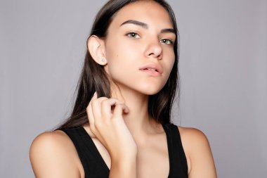 Gülümseyen bir çekici kameraya bakarak portre. Siyah elbise giymiş. Gri arka plan üzerinde poz. Temiz cilt, doğal makyaj ve beyaz dişler ile gülümseyen güzel kadın