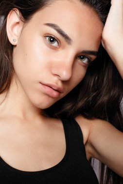 Gülümseyen bir çekici kameraya bakarak portre. Siyah elbise giymiş. Gri arka plan üzerinde poz. Temiz cilt, doğal makyaj ve beyaz dişler ile gülümseyen güzel kadın