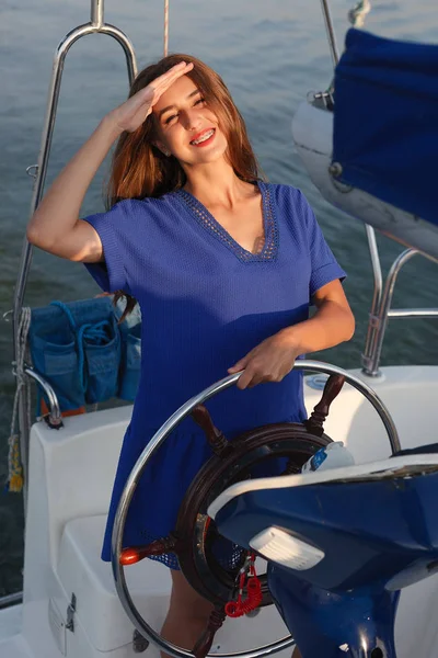 Attractive girl on a yacht at summer day. Close up of fashion portrait of stunning romantic woman posing yacht. Wearing an elegant dress, summer outfit. Blue sky. sunset