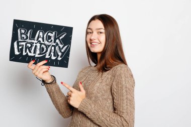 Alışveriş, perakende, siyah Cuma, satış, alışveriş ve insanlar kavramı - genç gülümseyen esmer kız siyah Cuma işareti tutuyor. Siyah Cuma satış.