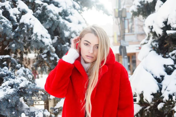 winter, fashion, people concept - fashion Portrait of a beautiful young woman walks around the city smiling red fur coat close-up snowflakes cold winter, breathe fresh air at frost winter day. sunset