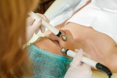 insanlar, Güzellik, spa, kozmetik ve teknoloji kavramı - güzellik uzmanı yordamı microcurrent terapi güzel, Genç bir kadının yüz derisinin bir güzellik salonu yapar