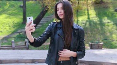 Güzel genç kadının saçları ile oynamak portre. Kız deri altına gider. Doğal makyaj ve onun uzun Rüzgar saçlarında kamera bakarken hareket sıralama ile genç ve güzel kız