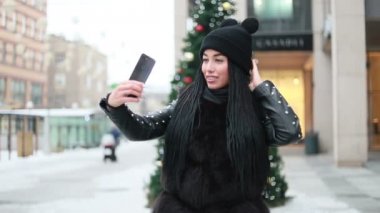 Kışın, Noel 'de, insanlar Noel' de açık havada cep telefonu kullanarak özçekim yapan bir kızın ışığa maruz kalma geçmişi olduğunu düşünüyor. Selfie zamanı, blog yazarı sosyal sayfası için video ve fotoğraf çekiyor.