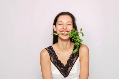 Maydanoz ile güzel gülümseyen kız. Moda gri arka plan üzerinde kadın fotoğrafı. Yakın çekim. Sağlıklı yaşam konsepti. Maydanoz birçok vitaminler içerir.