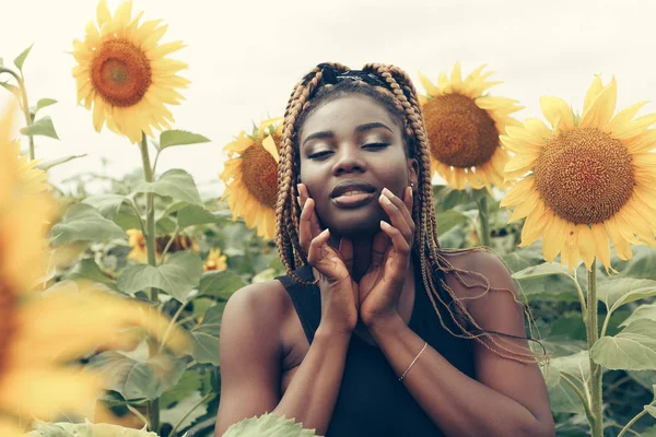 Афроамериканка в поле желтых цветов на закате — стоковое фото