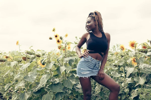 African American girl in a field of yellow flowers at sunset — Stock Photo, Image