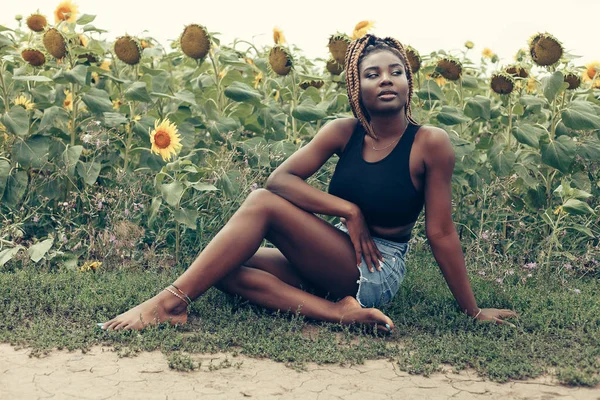 Chica afroamericana en un campo de flores amarillas al atardecer —  Fotos de Stock