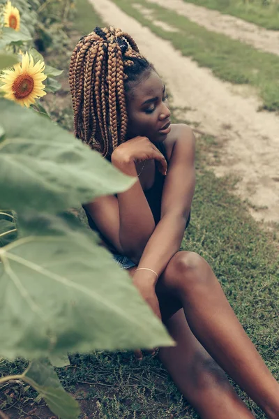 Menina afro-americana em um campo de flores amarelas ao pôr do sol — Fotografia de Stock