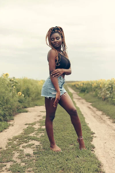 Afro-Américaine dans un champ de fleurs jaunes au coucher du soleil — Photo